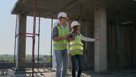 supervisor of a building under construction man discussing with engineer designer woman the progress of construction and examines a building plan.