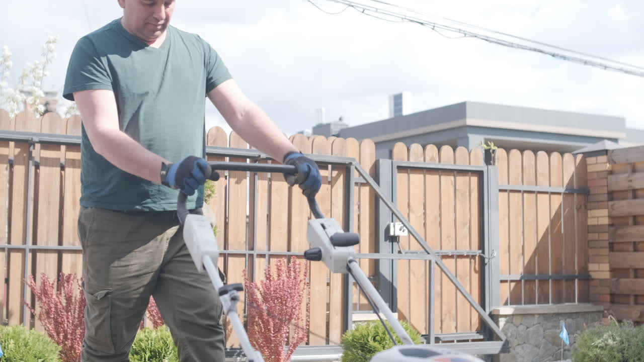 Man Mowing Green Grass Lawn with a Lawnmower in Backyard
