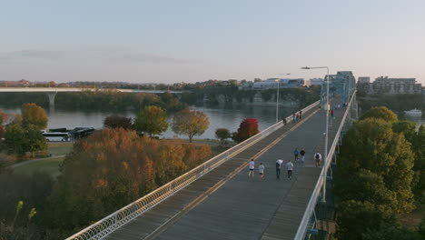 aerial footage during sunset following two runners running up the walnut street bridge to cross the tennessee river in chattanooga, tn