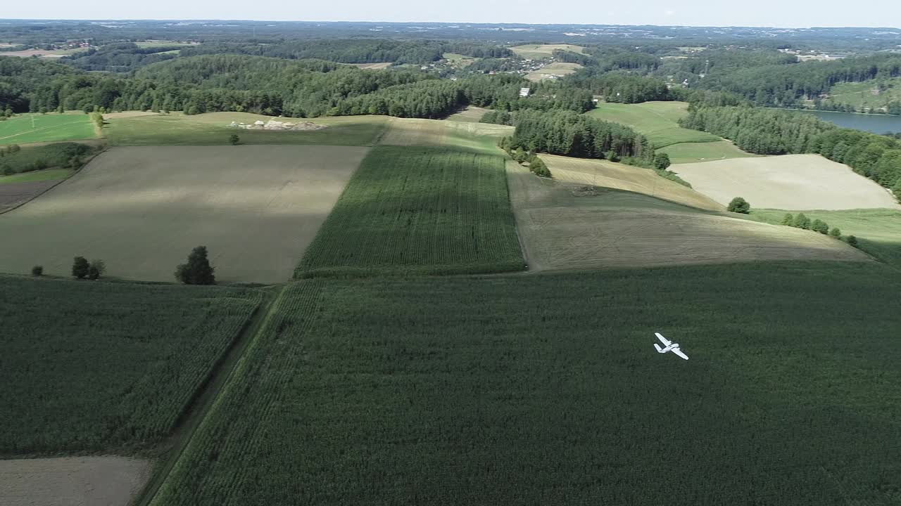 무성한 녹색 초원 위를 날아다니는 흰색 무선 조종 항공기 모델 - 공중 추적