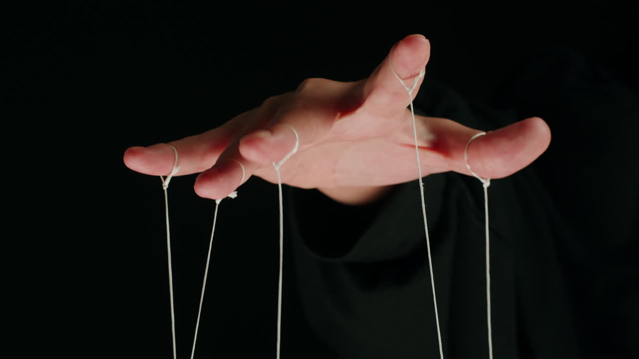 Close-up of Human Hand Manipulating Puppet Strings