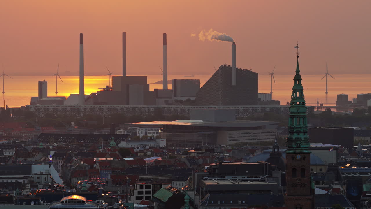 Aerial drone view of the skyline of Copenhagen, Denmark with Amager Bakke and offshore wind turbines at sunrise