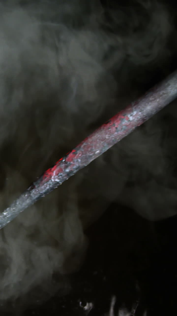 primer plano de un herrero enfriando una barra de hierro en agua