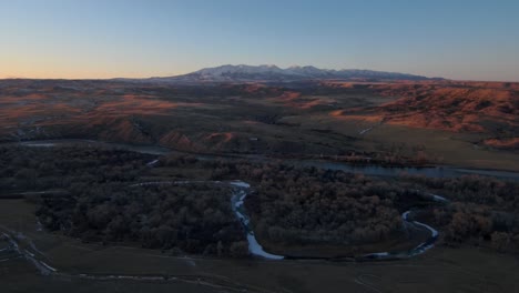 aerial view flying away from mountains and a river at sunset in montana