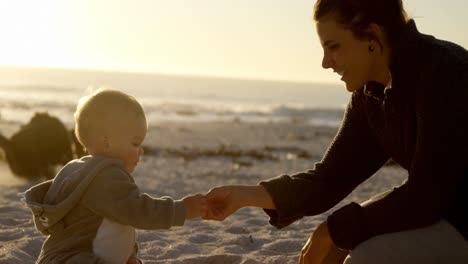 mother playing with her baby boy in the beach 4k