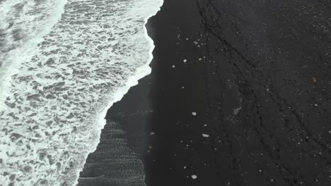 Top-down-aerial-of-diamond-beach-in-iceland-with-waves-and-ice-cubes