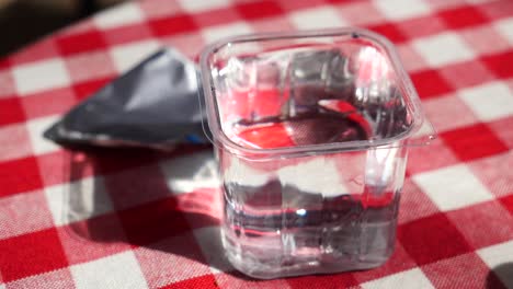 a glass of water on a red and white checkered tablecloth