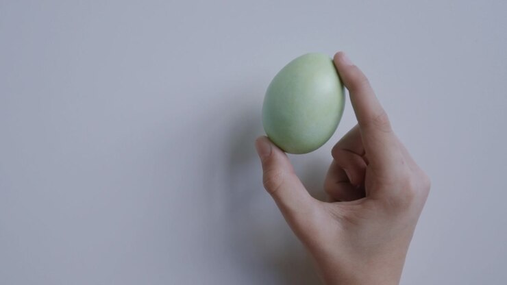 Hand holding a pastel green Easter egg