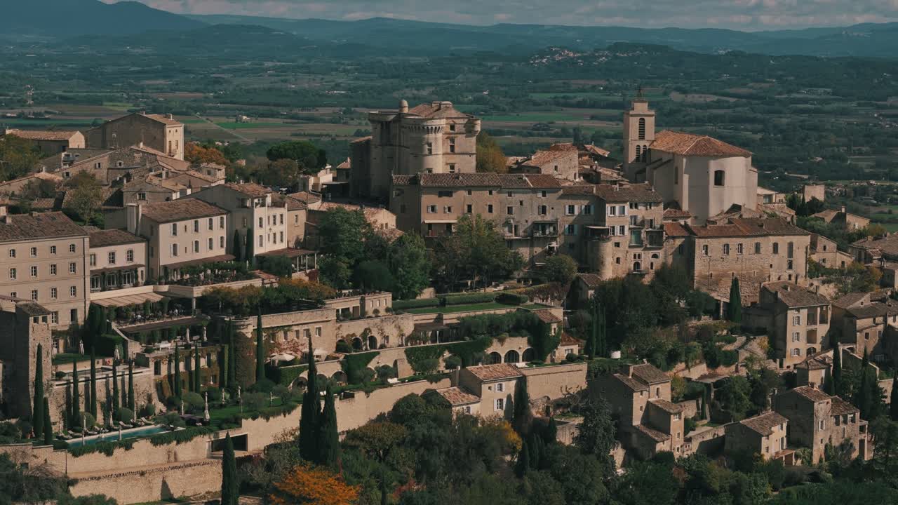 Aerial circling right of Gordes, France, surrounded by lush greenery and hilltop views