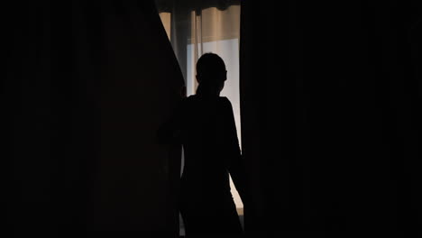 Silhouette-Einer-Frau,-Die-Den-Vorhang-Am-Fenster-Schließt