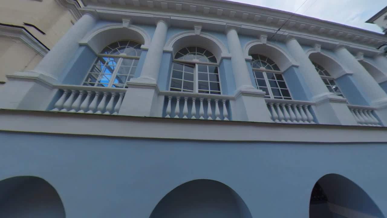 Architectural views of a blue and white building with a balustrade, showing an urban street scene with people