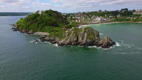 drone flies forward over water toward rocky coastline near trestignel beach in perros-guirec