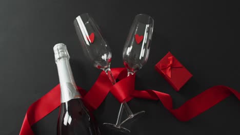 copas de champán y botella con regalo y cinta roja en el día de san valentín
