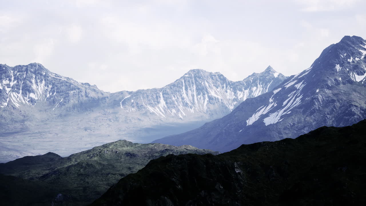 Majestic snow capped peaks rise under a serene cloudy sky in the mountains