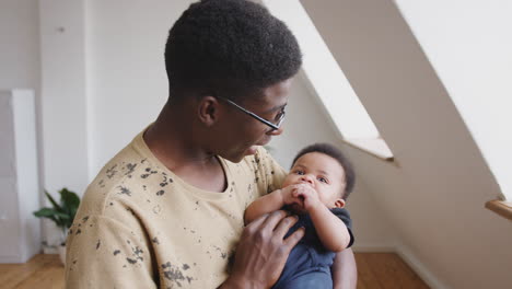 close up of loving father holding newborn baby son at home in loft apartment