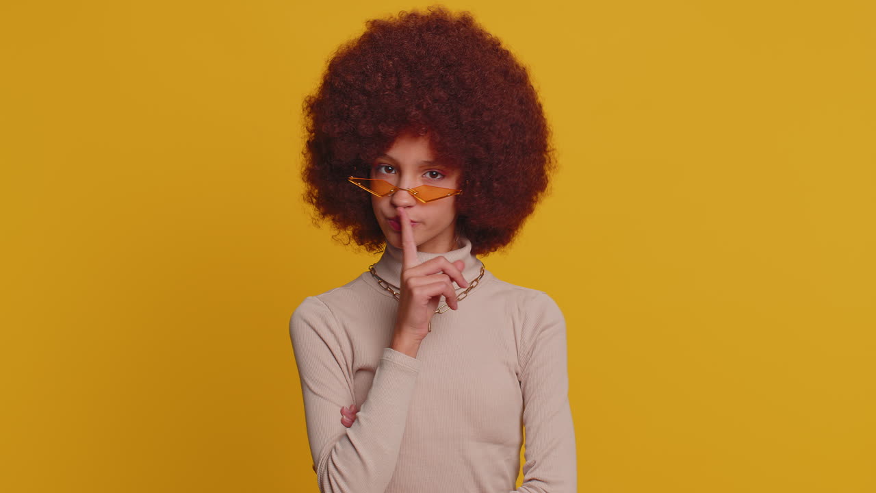 Preteen child girl presses finger to lips makes silence hush sign do not tells gossip secret, quiet