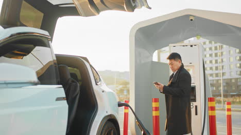 hombre cargando un coche eléctrico en una estación de carga