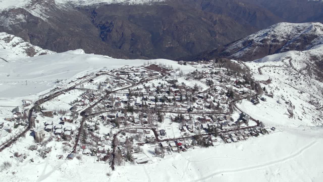 vista aérea que establece el pueblo montañoso de farellones completamente nevado en un día soleado, cúspide de las montañas de los andes, chile