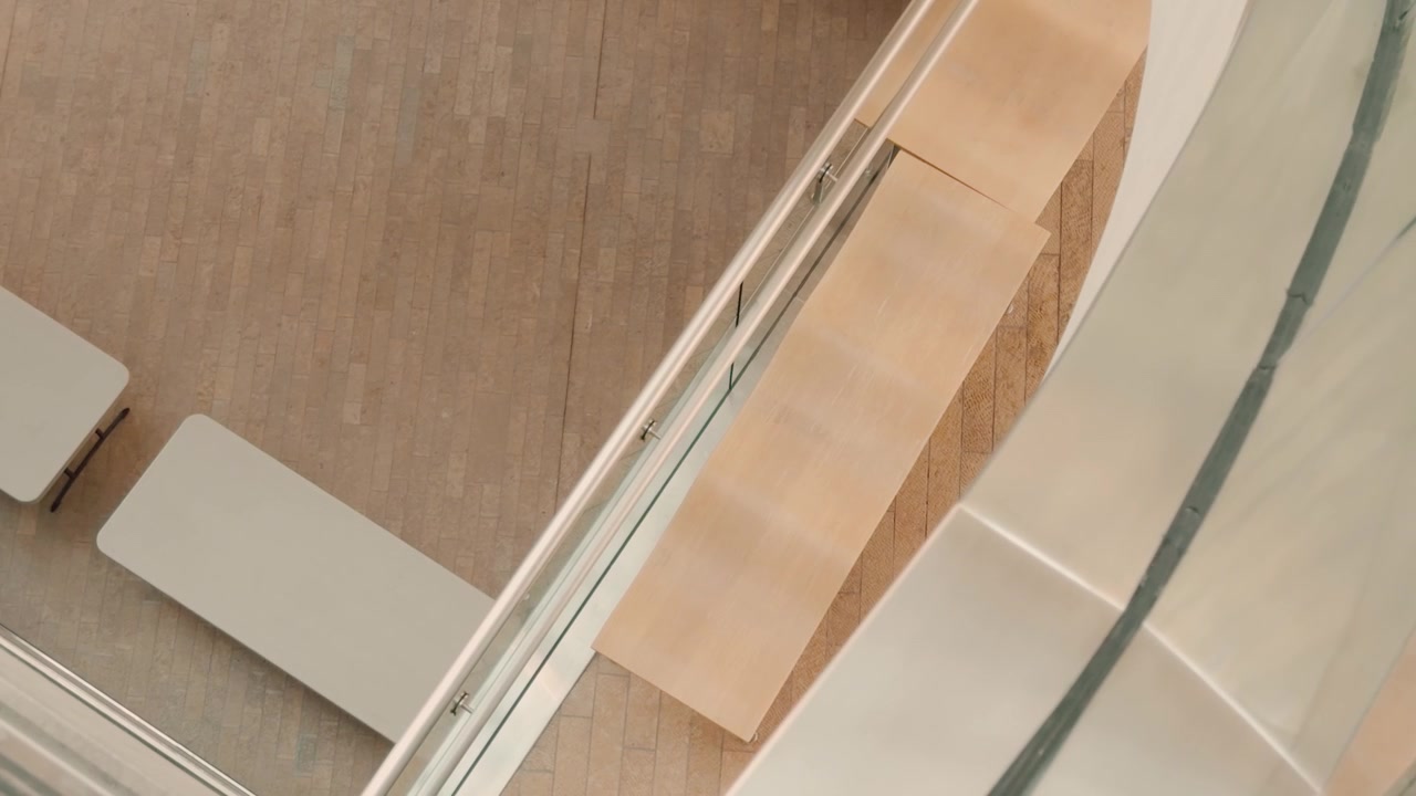 Top-down glide across indoor benches ending behind a railing.