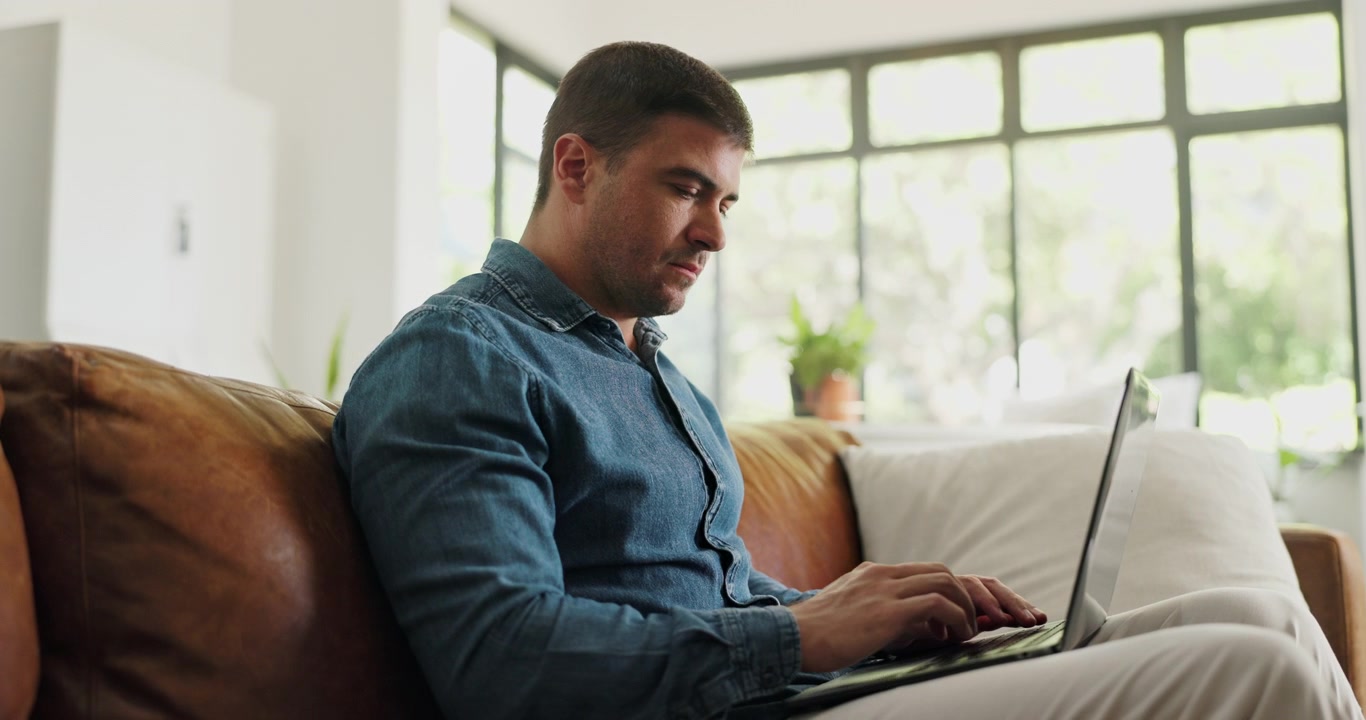 Man Working on Laptop While Sitting on Leather Sofa