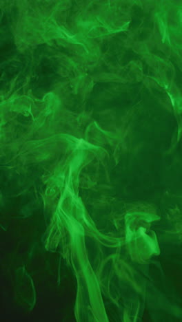 video vertical de humo blanco con luz verde moviéndose sobre un fondo negro