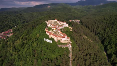 Zitadelle-Rasnov-Inmitten-Grüner-Wälder-Unter-Klarem-Himmel,-Tageslicht,-Luftaufnahme