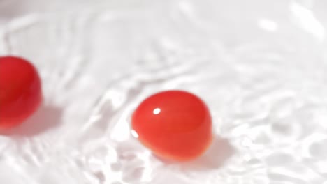 small tomatoes falling into a container with water for cleaning