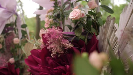 dolly shot of red flowers and pastel roses on a wedding arch with crepe blooms