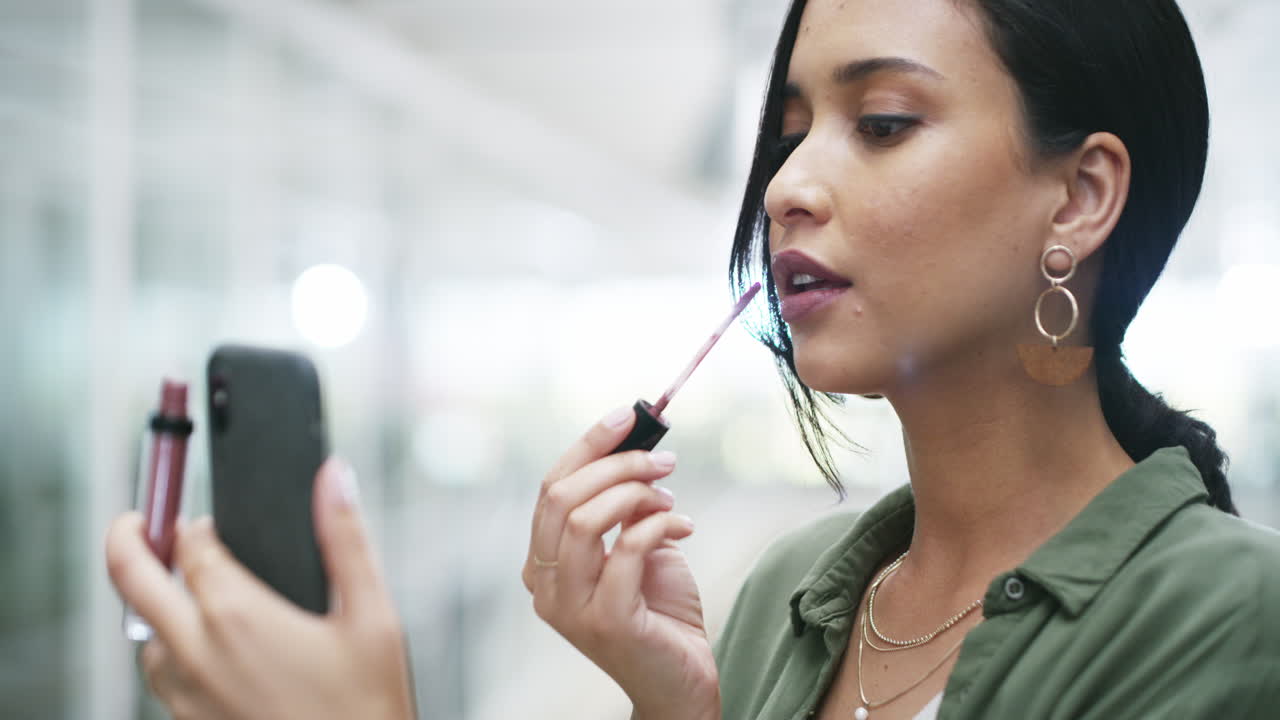 mujer aplicando lápiz labial usando el teléfono