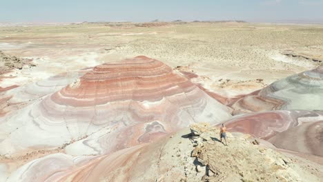 lonely shirtless man walking on peak in dry desert mars look alike landscape on hot summer day, drone aerial view