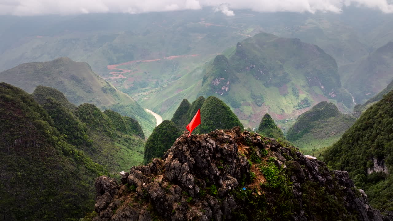 Panoramic View of a Mountain Range in Vietnam with a Red Flag on a Peak