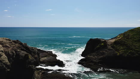 As-the-wave-breaks-on-the-rocks-water-becomes-foamy-as-it-rushes-into-a-rocky-inlet