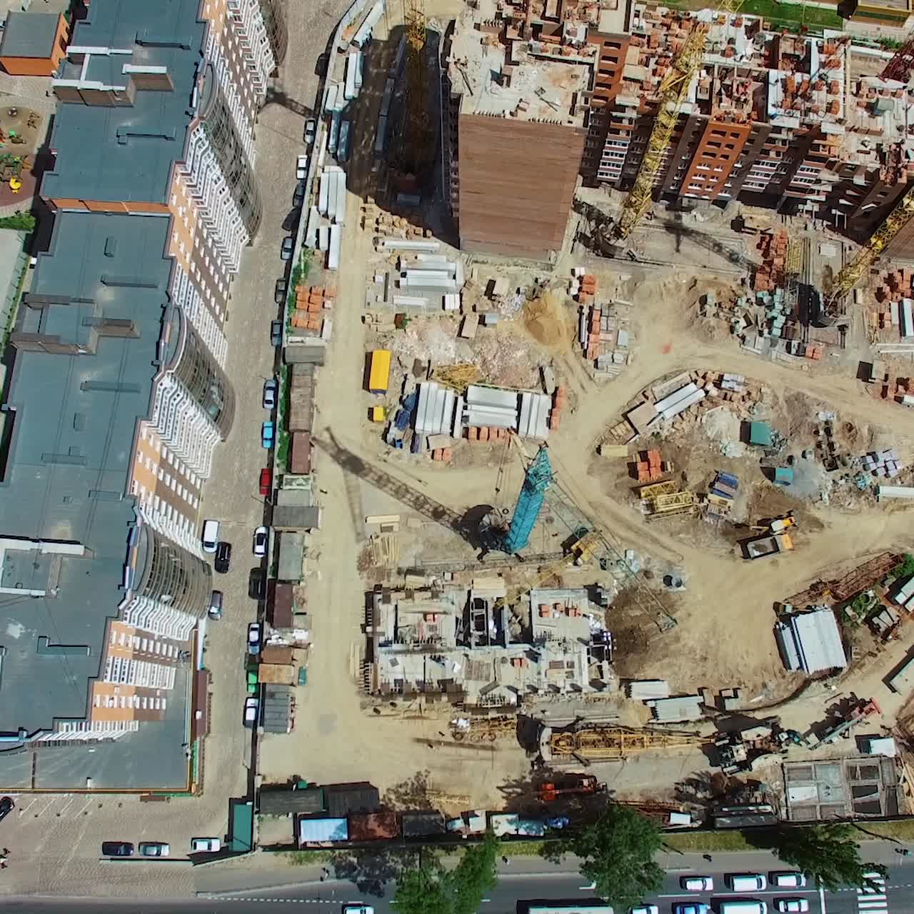 Top aerial view of a construction site in the city. View from above on roofs of newly built high-rise flats next to the construction works. Urban background.