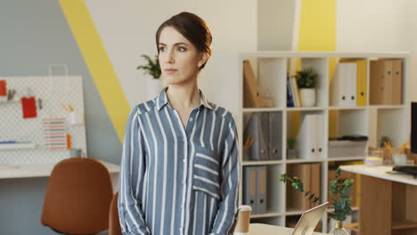 portrait shot of the young attractive woman with hands crossed in front standing and posing in the urban office