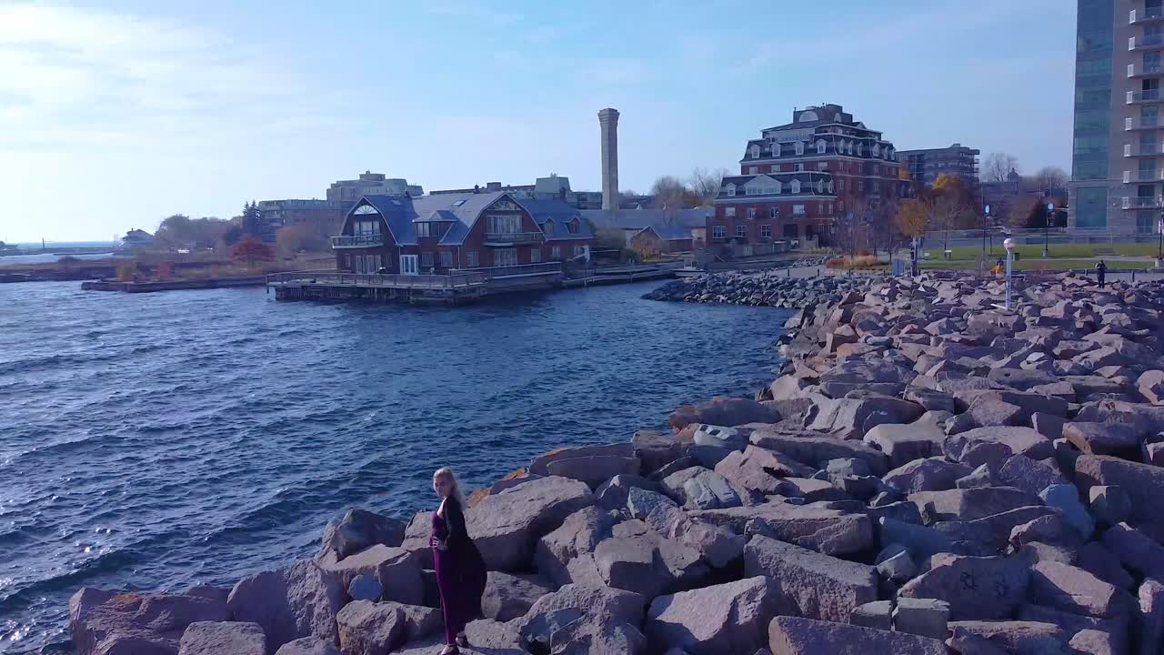 靠近海岸線的岩石上站立的空中年輕女人