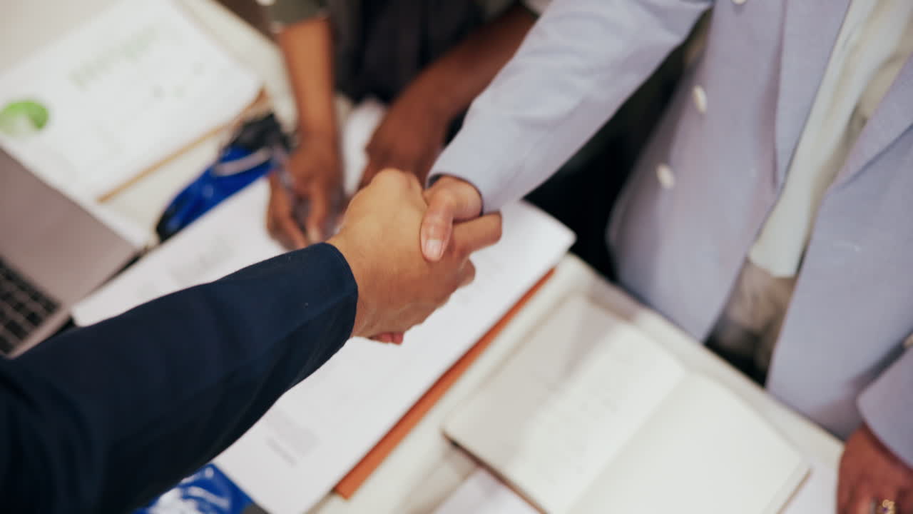Profesionales de negocios dándose la mano sobre documentos