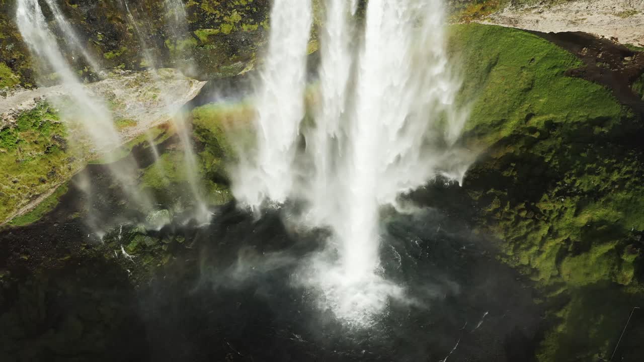 salpicaduras de agua en la piscina debajo del borde de la cascada en islandia, creando un arco iris