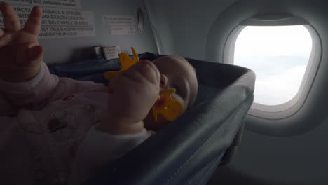 playful baby with toy in special plane bassinet