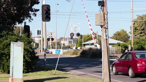 train crossing with barriers lowering and car waiting