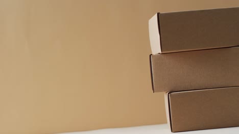 Video-of-stacked-cardboard-boxes-with-copy-space-over-brown-background