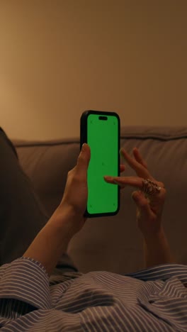 mujer acostada en el sofá usando el teléfono con pantalla verde