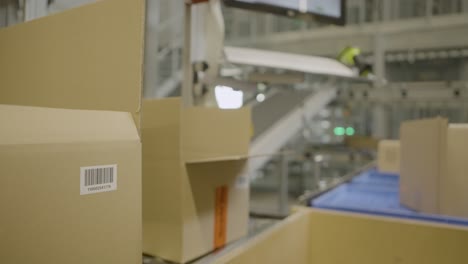 gloved hand scanning a barcode on a cardboard box with a handheld scanner in a warehouse setting