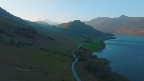 CRUMMOCK-WATER-Lake-District-Unesco-National-Park,-Aerial-Sunrise-push-forward-across-lake-early-morning,-sun-dappling-mountains