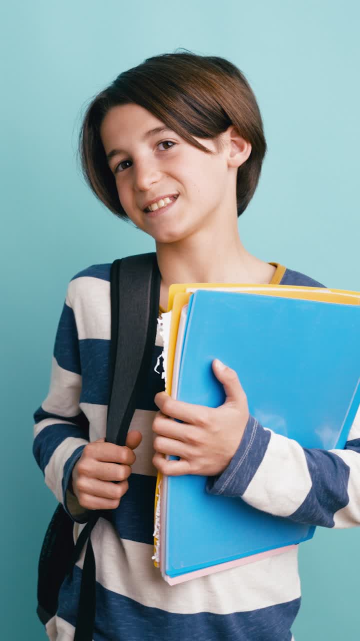 Niño joven feliz sonriendo con mochila y carpetas escolares