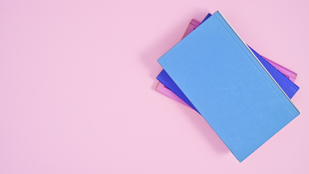 Pale of pastel hardcover books ordered one on other disappear and appear on pastel pink theme. Stop motion flat lay