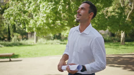 happy man holding blueprint sunshine greenery park closeup.  businessman