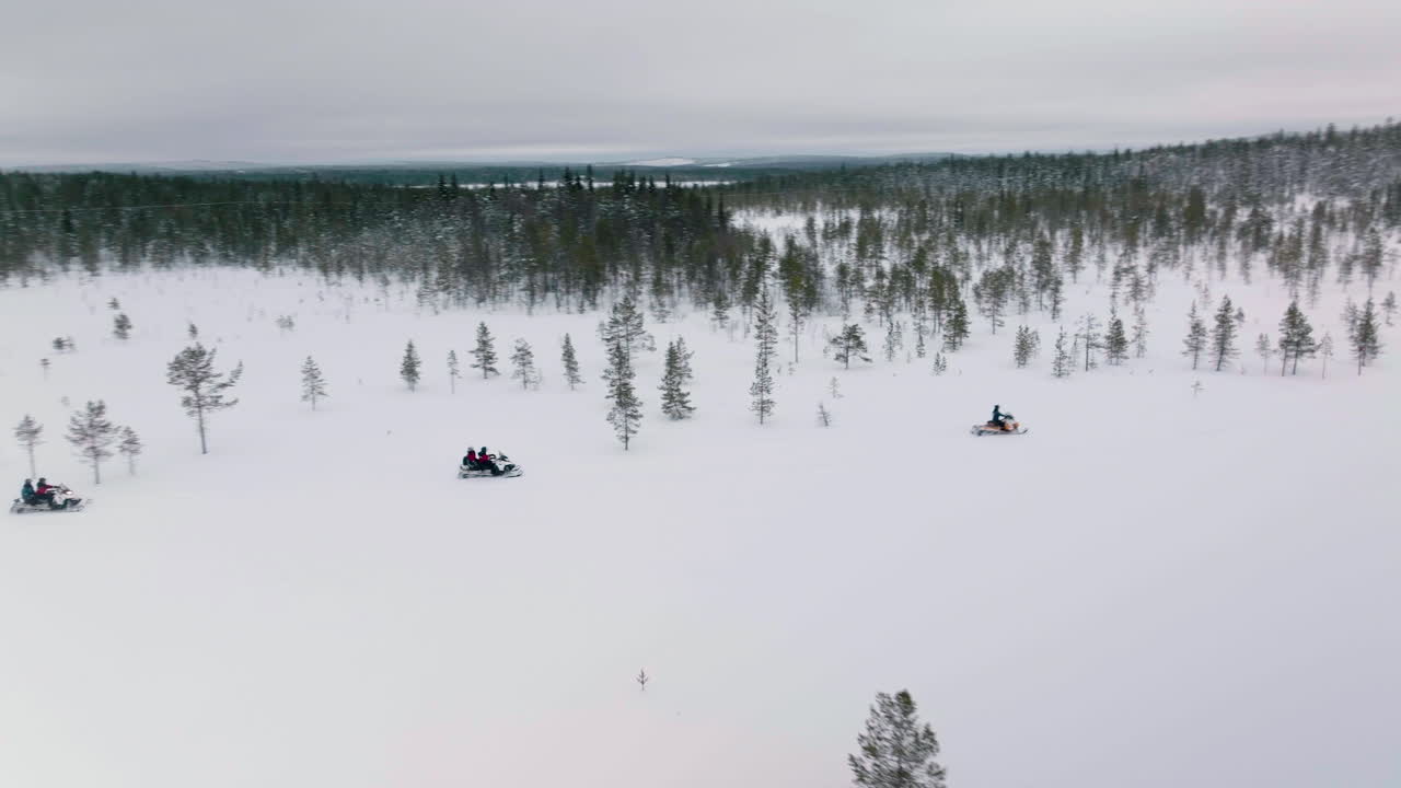 Gruppe mennesker på snøscooter i et vinterlandskap rundt byen Muonio i Lappland, Finland på en vinterdag
