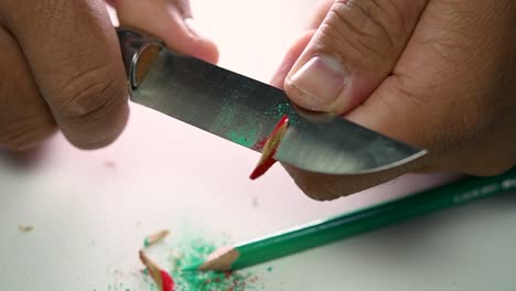 Footage-of-hands-slowly-sharpening-a-pencil-and-some-coloured-pencils-with-a-sharp-knife