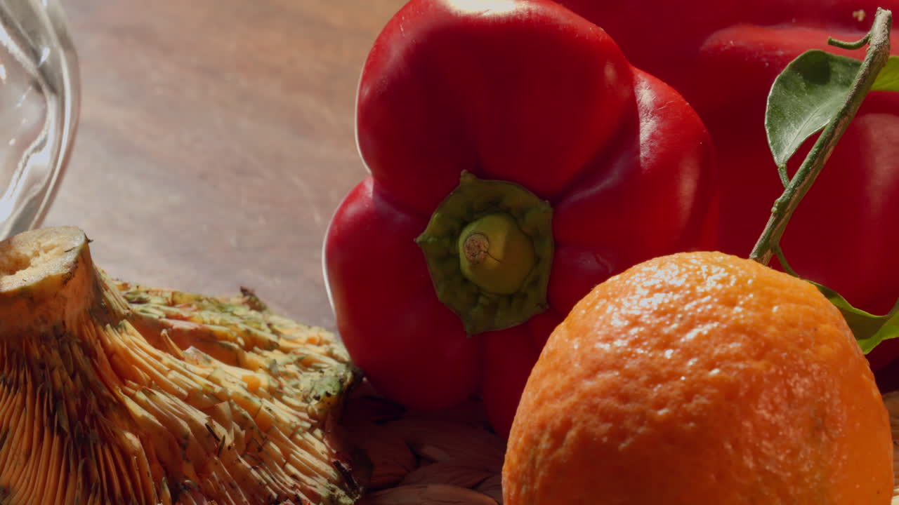 Fungo fresco, peperone rosso e arancia su una superficie di legno.