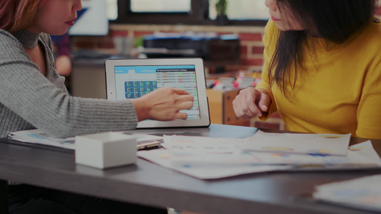 Coworkers looking at stock market statistics on tablet